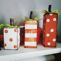 three painted wooden blocks sitting on top of a white shelf next to orange and green decorations