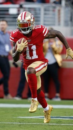 a football player running with the ball in his hand and people watching from the stands behind him