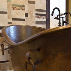 a bath tub sitting next to a sink in a bathroom with tile on the walls