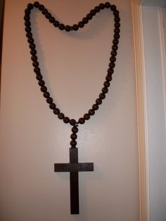 a rosary with a wooden cross hanging from it's side on a white wall