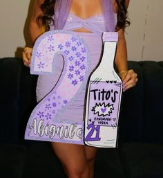 a woman in a purple dress holding up a cardboard sign with the number twenty two on it