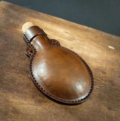 a brown leather bottle holder sitting on top of a wooden table