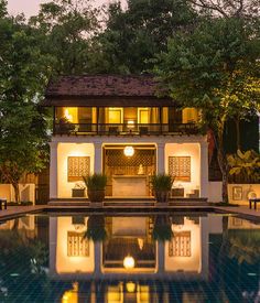 an outdoor swimming pool at night with lights on the building and trees in the background