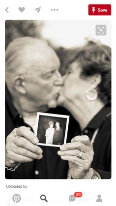 an older couple kissing while holding up a photo