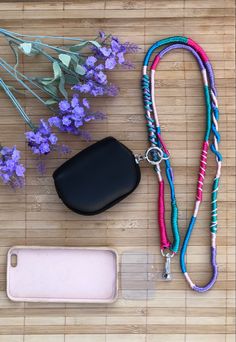 a cell phone and lanyard on a bamboo mat with purple flowers in the background