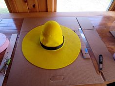 a yellow hat sitting on top of a cardboard box next to a pair of scissors