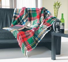 a plaid blanket sitting on top of a black table next to a bottle of wine