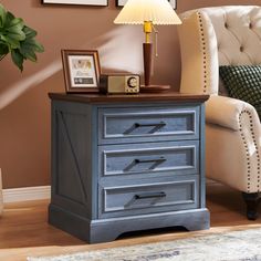 a blue chest of drawers in a living room next to a chair and framed pictures