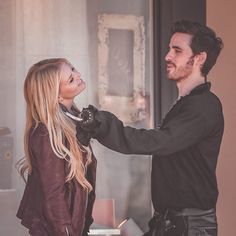 a man and woman standing next to each other in front of a door holding scissors