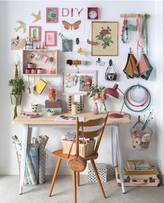 a desk with lots of different items on the wall and pictures hanging up above it