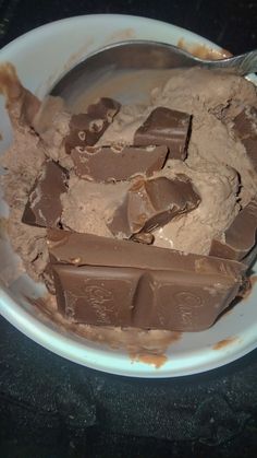 a white bowl filled with ice cream and chocolate chunks on top of a black table