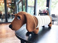 a knitted dog sitting on top of a wooden table