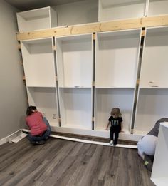 two children are sitting on the floor in front of bookshelves that have been built