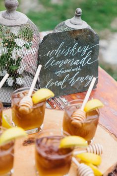 some drinks are sitting on a table with honeycombs and strawberries in them