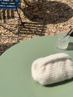 a knitted mitt sitting on top of a table next to a glass of water