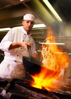 a chef is cooking on the grill with flames coming out of his skillet and holding a spatula