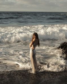 a woman is standing in the water at the beach