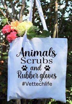 an animal scrubs and rubber gloves tote bag hanging from a tree with flowers