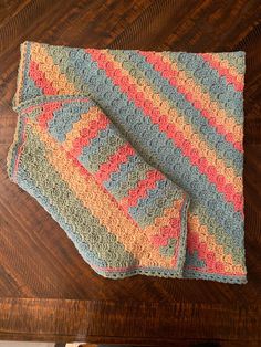 two crocheted blankets sitting on top of a wooden table