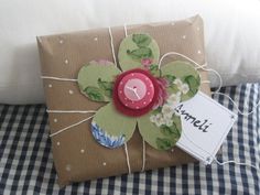 a gift wrapped in brown paper with a flower on it and a name tag attached