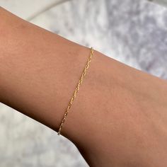 a woman's arm with a gold chain bracelet on top of her left arm