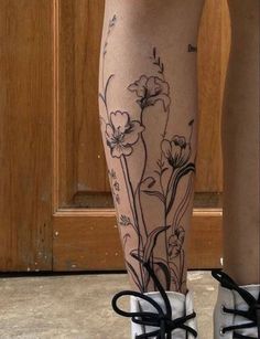 a woman's legs with flowers on them and black laces around the ankles