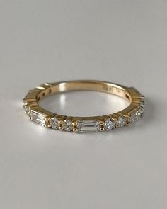 a yellow gold wedding band with baguettes set in the middle, on a plain surface