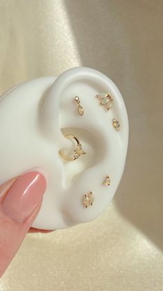 a person holding an earring with several small jewels on it's side and the top part of their ear