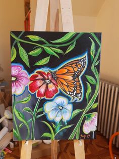 an easel with a painting on it that has flowers and a butterfly painted on it