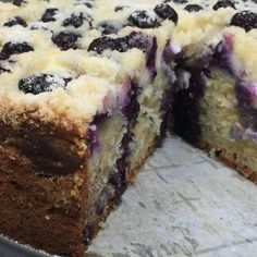 a close up of a cake with blueberries on it and one slice cut out