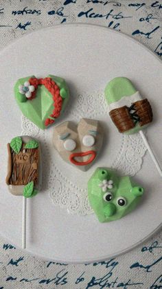 there are some green and white decorated cookies on a plate with toothpicks in the shape of faces