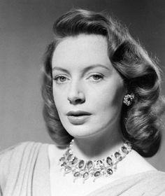 an old black and white photo of a woman in a dress with pearls on her neck