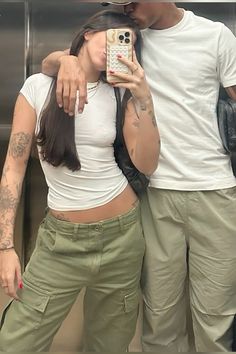 a man and woman taking a selfie in front of an elevator with their cell phone