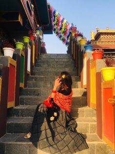 a woman is sitting on the stairs taking a photo