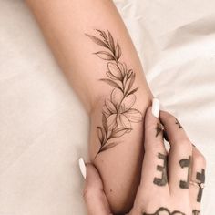 two hands holding each other with tattoos on their fingers and the one has a flower tattooed on it