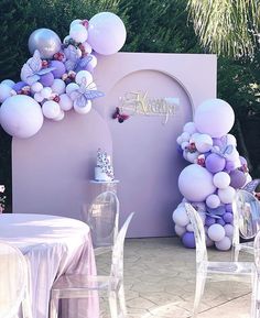 an outdoor party with balloons and flowers on the wall, table cloths and chairs