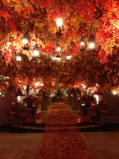 the walkway is decorated with lanterns and fall colored leaves on it's sides, along with lights hanging from the ceiling