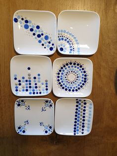 four blue and white plates with dots on them sitting on a wooden table next to a bowl