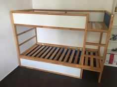 a wooden bunk bed sitting next to a book shelf in a room with white walls