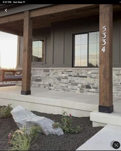 the front porch of a house with stone and wood columns