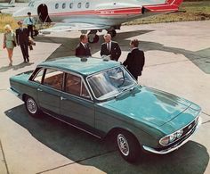 an old photo of men in suits standing next to a green car with the door open