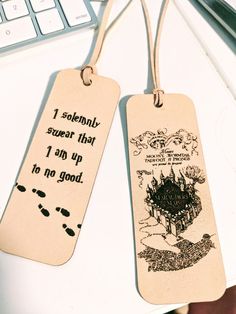 two bookmarks with writing on them sitting next to a keyboard