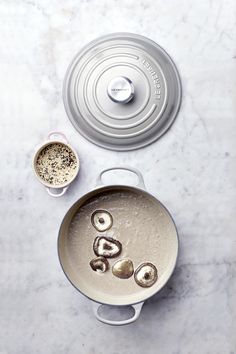 an overhead view of a pot with food in it on a marble counter top next to a measuring cup