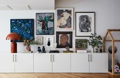 there are many pictures on the wall in this living room, including paintings and vases