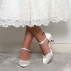 a close up of a person's shoes wearing white wedding dress and high heels