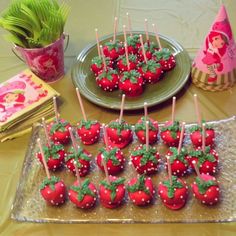 there are strawberries on the plate and cupcakes on the table