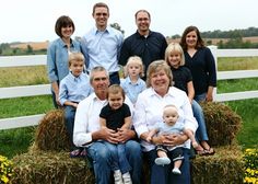 a group of people sitting on top of hay bales in front of a fence