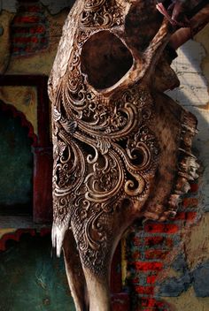 an animal skull with intricate carvings on it's face and back end, against a colorful background