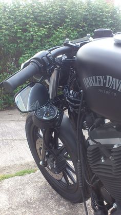 a black motorcycle parked next to a bush