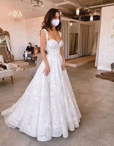 a woman in a white wedding dress wearing a face mask